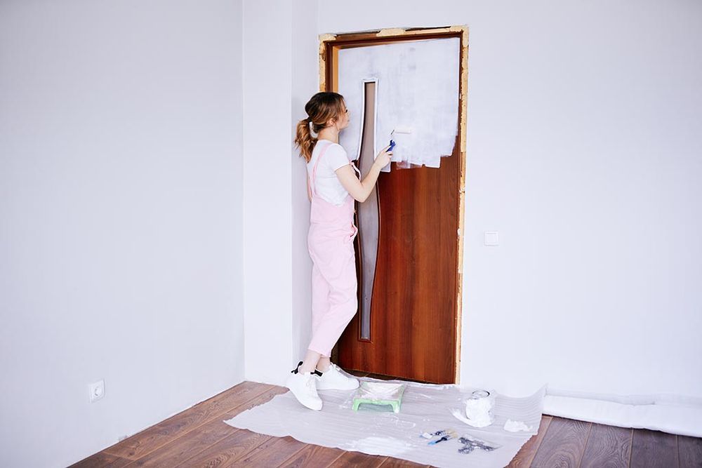 Foto de una chica pintando una puerta en color blanco